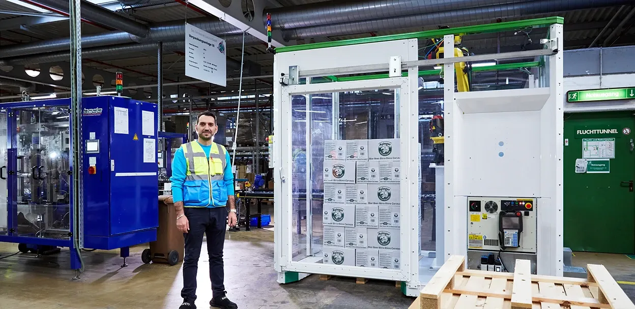 Sirl Mitarbeiter vor einer Palettierzelle für Kartons