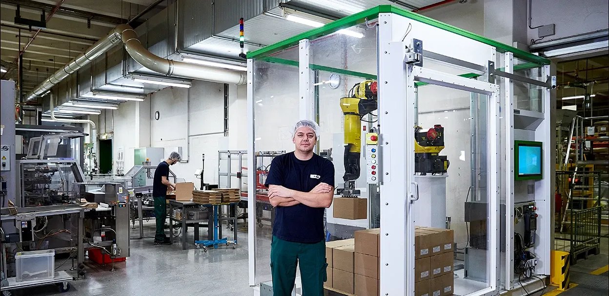Wollenhaupt Tee GmbH Mitarbeiter vor der Palettierzelle in der Produktion